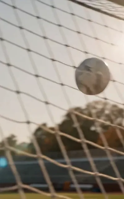 A striker's shot slams into the net at close range during a practice drill, the white goal frame filling the frame